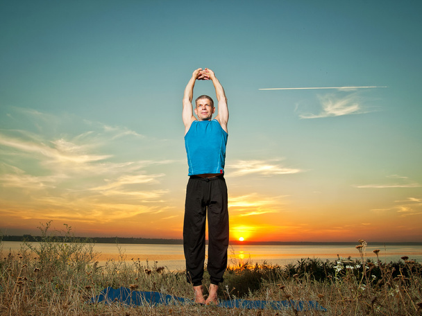 улыбающийся человек делает упражнения йоги на открытом воздухе
 - Фото, изображение