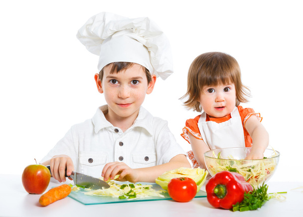 Two smiling kids mixing salad - Fotó, kép