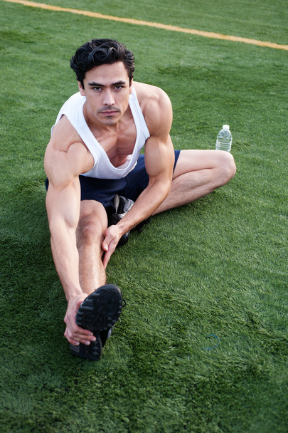 Handsome, young latino athlete stretching - Fotó, kép