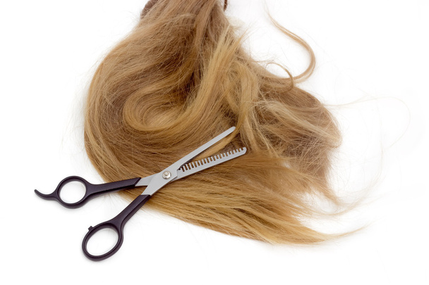 Hairdressers scissors against the backdrop of strand of female h - Foto, Bild