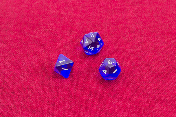 Trois dés de rôle polyèdres sur table avec tissu rouge
 - Photo, image