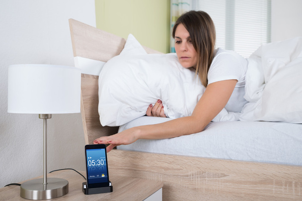 Mulher na cama Snoozing alarme
 - Foto, Imagem