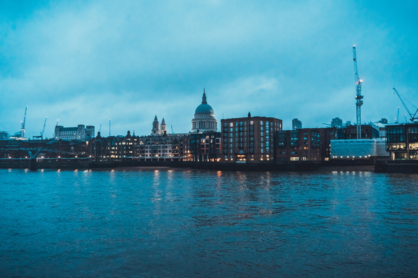 City Skyline with View of Historic St Pauls Cathedral Dome and Construction Cranes Towering Above Low Rise Buildings Along Thames River on Cloudy Evening in London, England, UK - Photo, Image