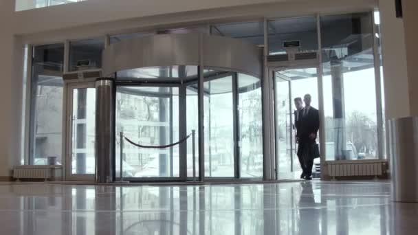 Dos hombres de negocios y una mujer se reúnen en la sala del hotel
 - Metraje, vídeo