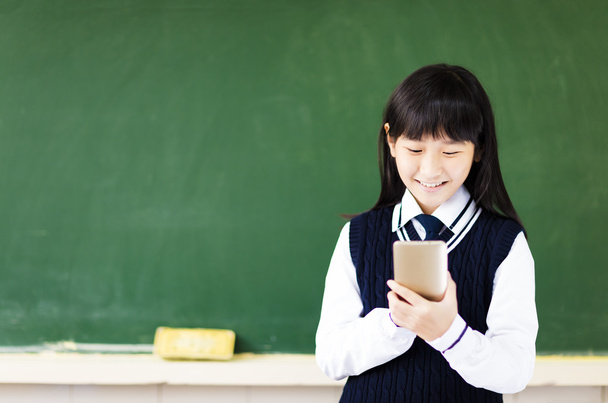 onnellinen opiskelija tyttö älypuhelimen luokkahuoneessa
 - Valokuva, kuva