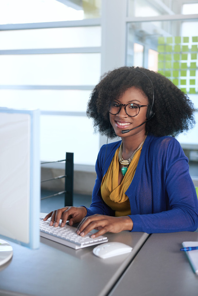 Portrait of a smiling customer service representative with an afro at the computer using headset - Фото, зображення