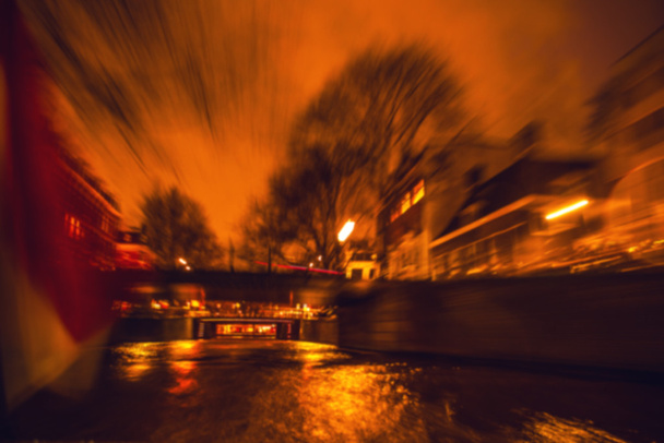 Отражения ночного освещения в Амстердамских каналах от движущегося круизного судна. Размытое абстрактное фото в качестве фона
. - Фото, изображение