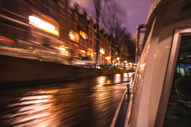 Nacht verlichting reflecties in Amsterdam kanalen verplaatsen cruise boot. Wazig abstracte foto als achtergrond. - Foto, afbeelding