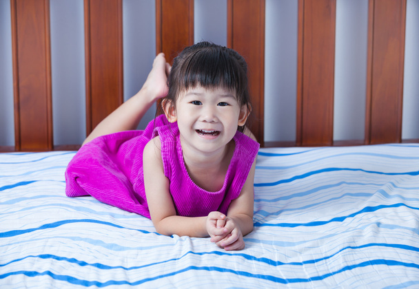 Πορτρέτο του χαριτωμένο κορίτσι ξαπλωμένο ξυπόλητος στο κρεβάτι στο υπνοδωμάτιο. - Φωτογραφία, εικόνα