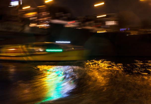 Reflejos de iluminación nocturna en los canales de Amsterdam desde el crucero en movimiento. Foto abstracta borrosa como fondo
. - Foto, Imagen