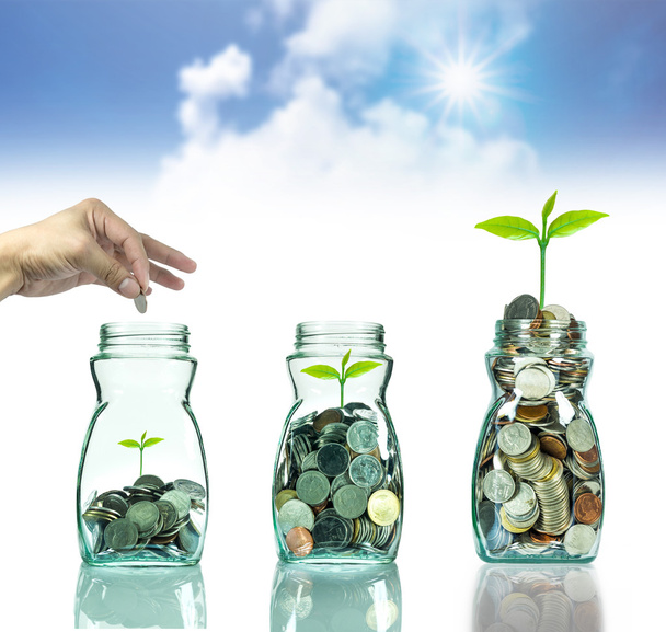 Рука кладе мікс монети і насіння в прозору пляму на розмитому блакитному небі з хмарним фоном, концепція інвестиційного зростання бізнесу
 - Фото, зображення