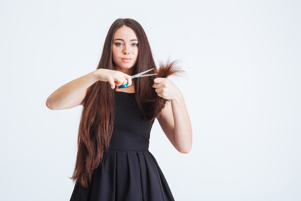 Ernsthafte Frau schneidet Splitterspitzen ihrer langen, zerbrechlichen Haare - Foto, Bild