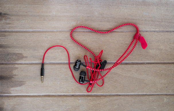 Portable audio earphones with heart Crochet on wood background - Photo, Image