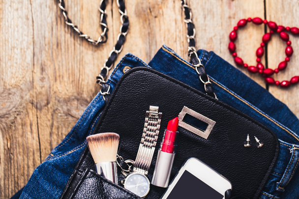Accesorios de moda para una niña, reloj, pulsera, bolso, lápiz labial rojo, teléfono, cepillo sobre un fondo de madera
. - Foto, imagen