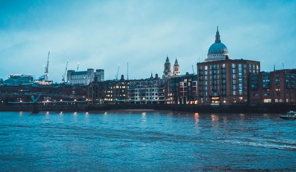 Tarihi St Pauls Katedrali ile Rıhtım Kenti Skyline. Londra, İngiltere, Uk 'ta bulutlu bir akşamda Thames Nehri boyunca alçak katlı binaların üzerinde görülebilir. - Fotoğraf, Görsel