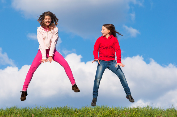 Meninas adolescentes bonitos pulando com alegria no dia ensolarado da primavera
 - Foto, Imagem