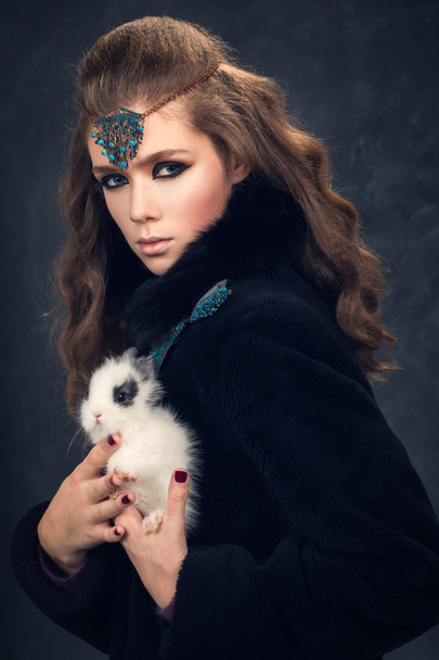 Portrait d'une fille en manteau de fourrure noire avec un lapin blanc
. - Photo, image