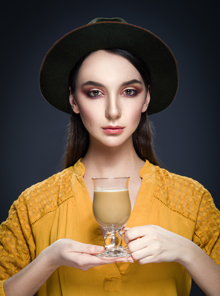 schöne junge Frau mit Hut und gelber Bluse mit Tasse Kaffee - Foto, Bild
