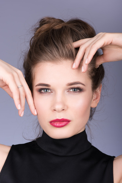 Closeup portrait of beautiful young woman in a black turtleneck. Touches face - Photo, image