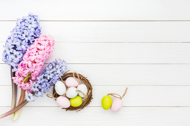 Jacinthes fraîches et œufs de Pâques décoratifs dans un petit nid sur une table blanche. Vue du dessus
 - Photo, image