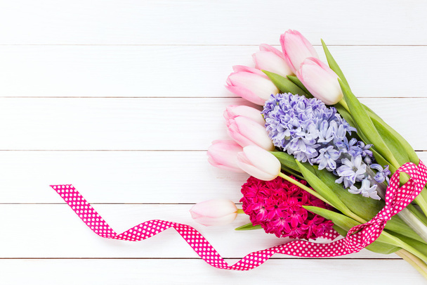 Ramo de flores de primavera decorado con cinta sobre fondo de madera blanca
. - Foto, imagen