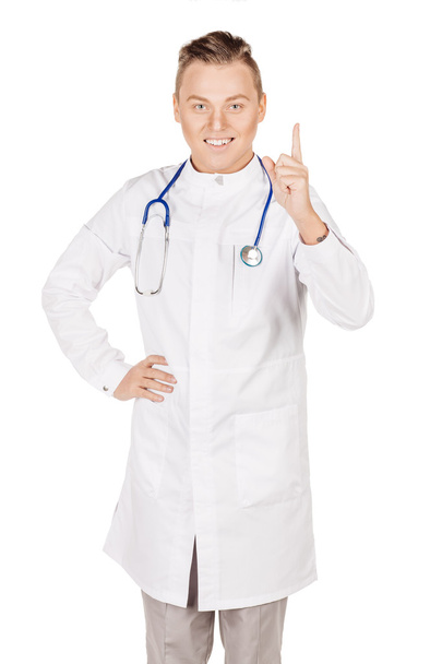 Young  male doctor in white coat and stethoscope finger point up - Foto, Bild