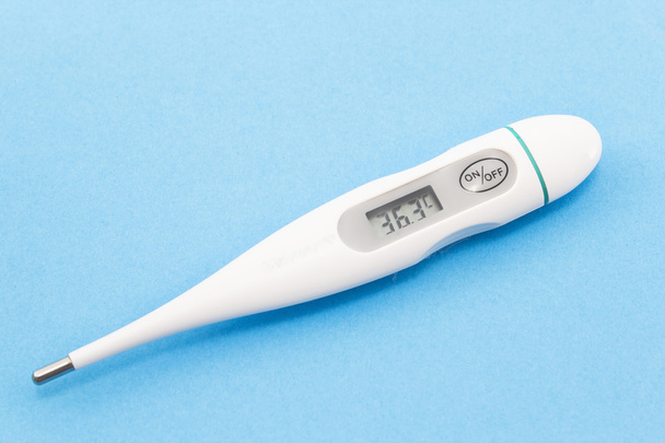 Digitale thermometer op een blauwe achtergrond - Foto, afbeelding