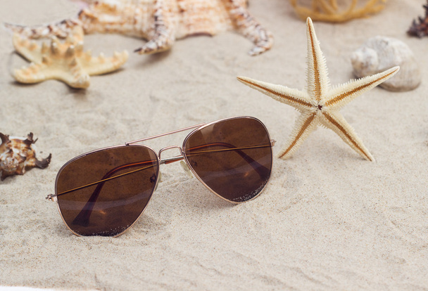  sun glasses and sheashell at sand close-up - Photo, Image