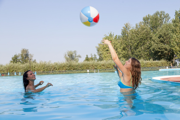 happy couple of girl relaxing in the pool playing with a ball - Foto, afbeelding