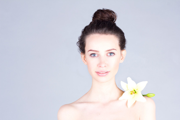 Smiling attractive woman with flower on her shoulder. Woman with clean skin. Skincare. - Foto, Imagen