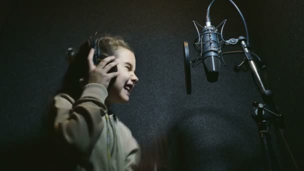 adolescente chica en auriculares cantando en micrófono audio profesional estudio de música
 - Metraje, vídeo