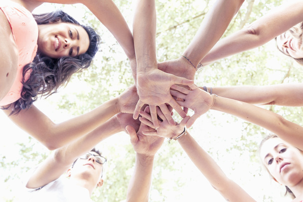 grupo de adultos jóvenes poniendo sus manos juntas en círculo
 - Foto, imagen