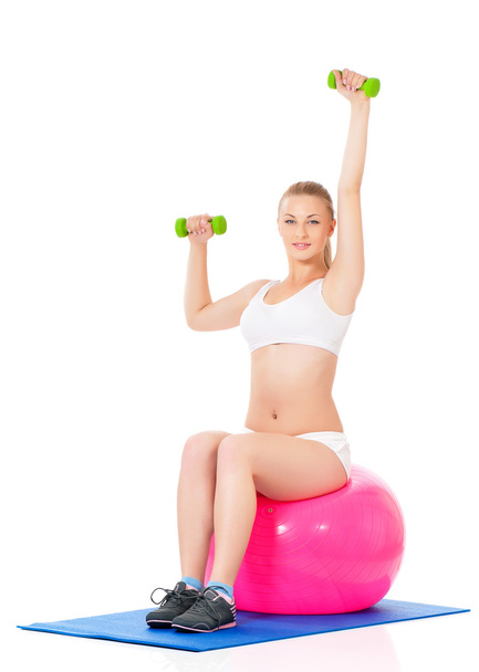 Mujer en ropa de fitness haciendo ejercicio con bolas de fitness y mancuernas
 - Foto, Imagen