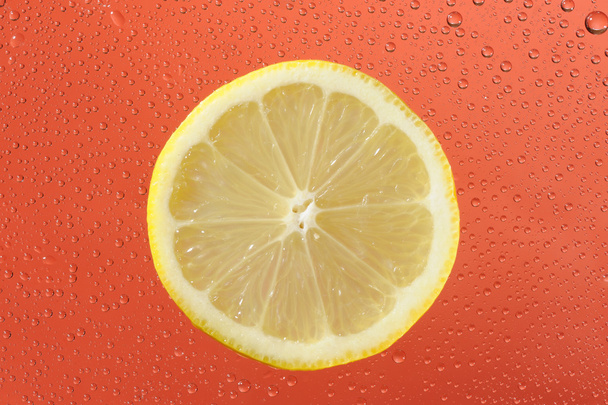 Lemon with many water drops on the red background - 写真・画像