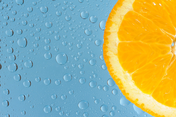Orange with many water drops on the blue background - Zdjęcie, obraz