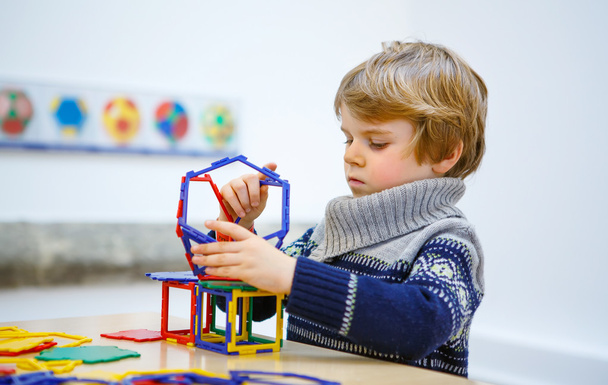 Niño pequeño construyendo figuras geométricas con bloques de plástico
 - Foto, imagen