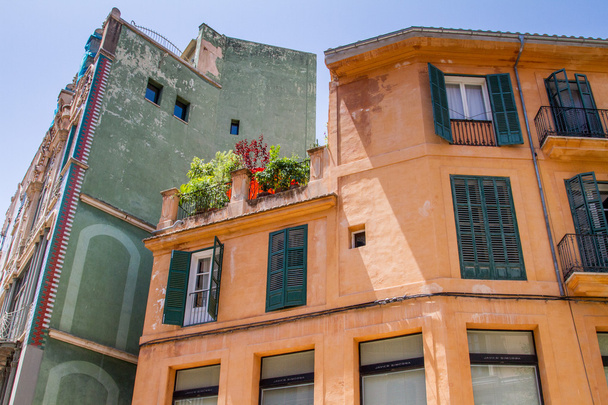 Alacsony szög kilátás színes régi lakások hatszögletű falak és gyönyörű zöld redőnyök ablakok - Fotó, kép