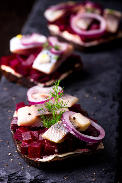 Sandwiches con arenque y remolacha en un plato de pizarra
 - Foto, imagen