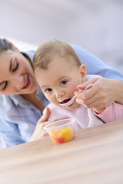 mother helping baby girl with eating - 写真・画像