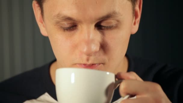 młody człowiek pije herbatę z filiżanki biały - Materiał filmowy, wideo