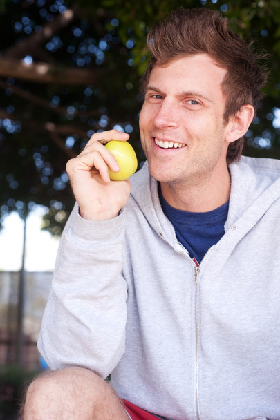 Portrait of a healthy young man holding apple - Photo, Image