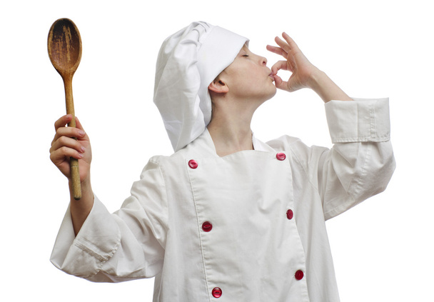 Young boy dressed as chef with wooden spoon on white background. - Foto, Bild