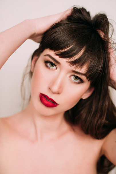 Όμορφη γυναίκα με κόκκινα χείλη στο studio, κάθεται γυμνή - Φωτογραφία, εικόνα