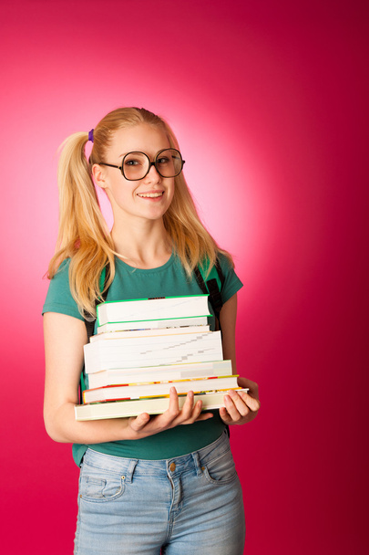 Curious, naughty, playful schoolgirl with stack of books and big - Fotografie, Obrázek