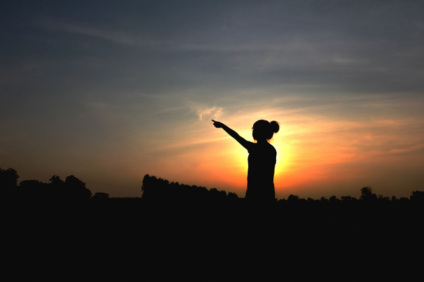 silhueta de mulher ao pôr do sol, postura em pé, perto de Dim
  - Foto, Imagem