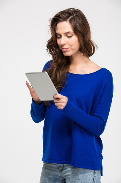 Smiling beautiful young woman standing and using tablet - Fotografie, Obrázek