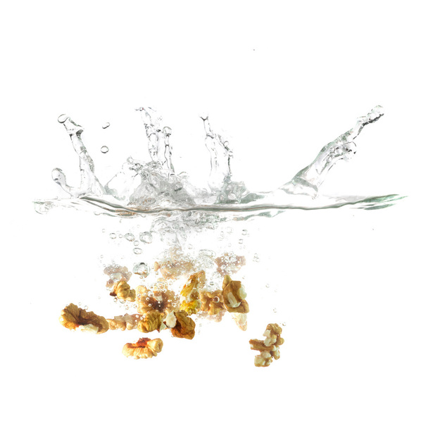 Walnuts splash on water, isolated on white background. - Foto, Imagem