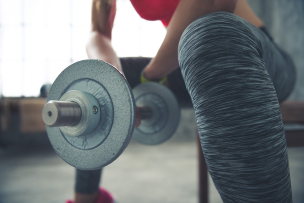 Closeup on fitness woman holding dumbbell in loft gym - Photo, Image