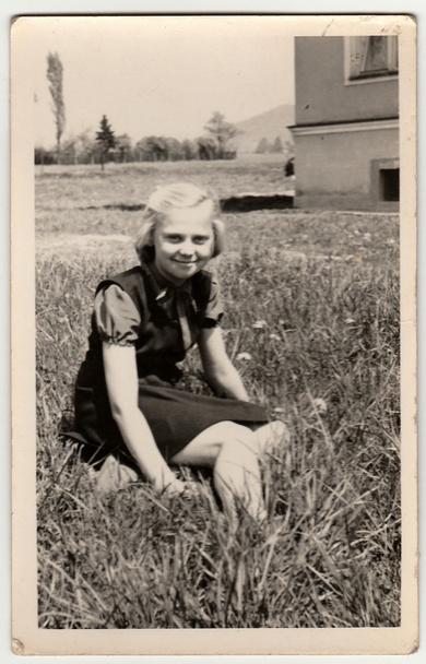 ヴィンテージ写真は、女の子が草の上に座って示しています. - 写真・画像