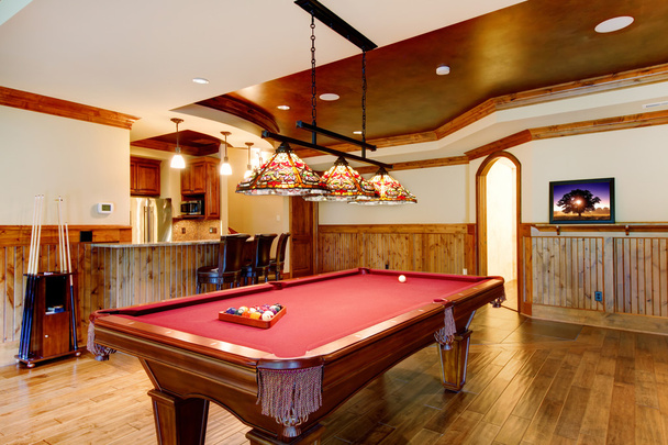 Large hardwood floor room with pool table and bar. - Фото, изображение